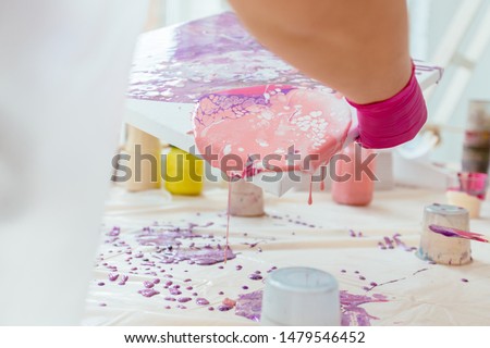 Woman painter holding hair dryer while female beginnres studying creating fluid acrylic abstract painting in art therapy class, dropping paints on canvas. Close up. Study, art therapy concept.