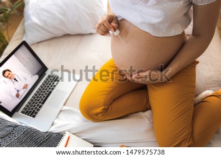 Expectant mother sitting on bed with and holding glass dropper stock photo