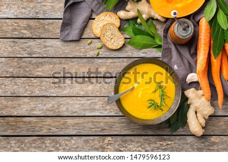 Healthy food, clean eating concept. Seasonal spicy fall vegetables creamy pumpkin and carrot soup with ingredients on a rustic wooden table. Top view flat lay copy space background