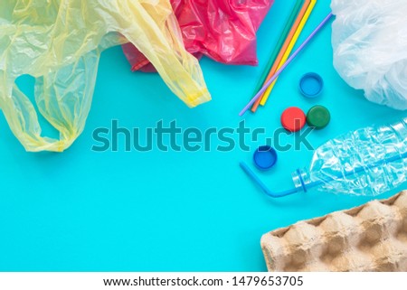 White single-use plastic bags and other plastic items on a yellow background. The concept of choice without plastic or environmental problems. Royalty-Free Stock Photo #1479653705