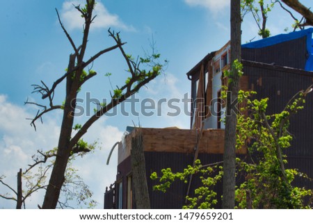 Awful tornado damage on a house and a blue tarp covering it. Royalty-Free Stock Photo #1479659201
