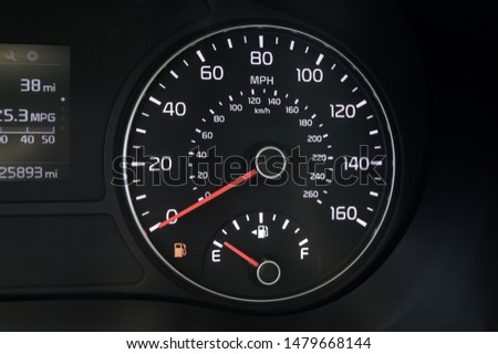 low key black and white car speedometer with fuel gauge on empty.