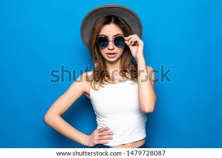 Fashion happy pretty smiling woman wearing a black hat and yellow knitted sweater over colorful blue background
