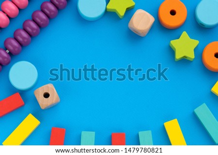 Top view on children's educational games, frame from multicolored kids toys on blue paper background. Wooden bricks, cubes, stars, circles, scores. Flat lay, copy space for text Royalty-Free Stock Photo #1479780821