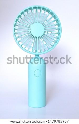 Close-up tosca colored portable mini fans. Easy to carry everywhere and rechargeable can be connected with a USB cable to powerbank. View from the front and standing. 
