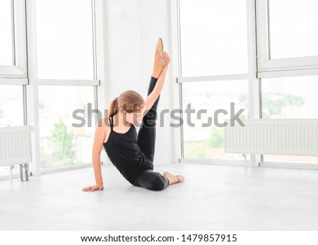 Young beatiful dancer is showing her flexibility in white dancing room