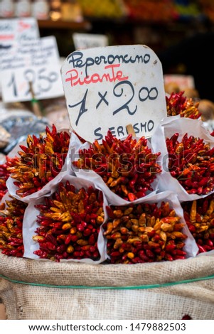 bunches of dried red hot chili peppers at an italian marketplace, peperoncino picante bouquet, dark red dried peppers Royalty-Free Stock Photo #1479882503