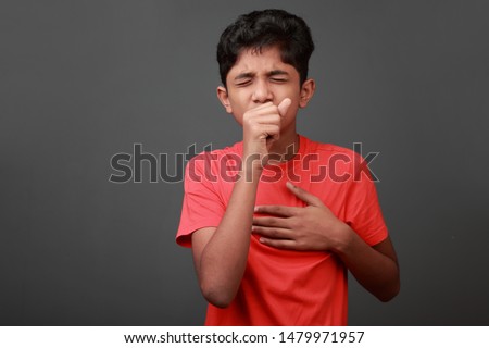 Boy coughs by closing his mouth by hands Royalty-Free Stock Photo #1479971957