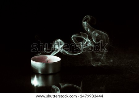 Smoke and extinct candle on a black background