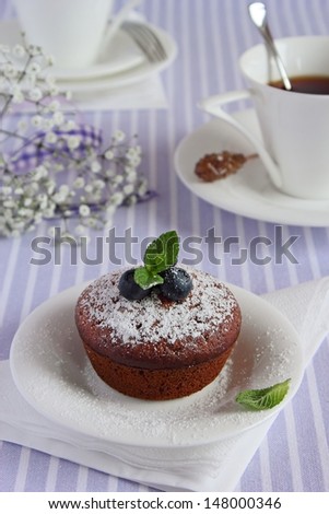 Muffin with blueberry and mint on the white saucer