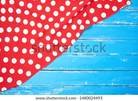 red textile towel with white circles on a blue wooden background, kitchen picnic background, copy space