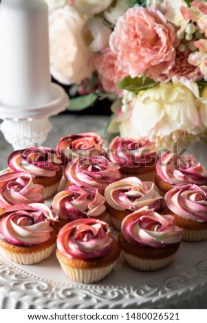 Beautiful colorful cup cakes with pink frosting on a cake stand