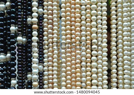 Black and white pearl beads background - perl necklaces hanging at the jewelry shop, horizontal image