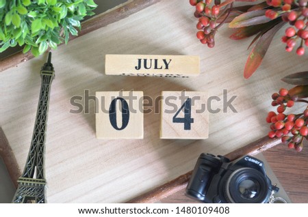 July 4. Date of July month. Number Cube with a flower camera and Sign wood on Diamond wood table for the background.
