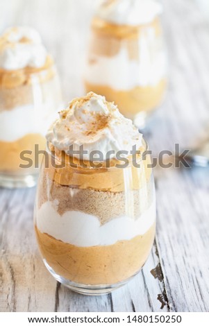 Homemade pumpkin trifle dessert made from pumpkin puree, cream cheese, cookie crumbs and whipped cream. Extreme selective focus with blurred background.
