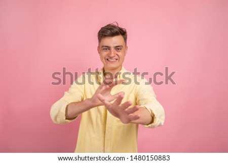 Surprised handsome man showing something on pink background