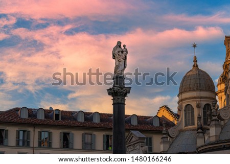 Sunset red clouds view of a Maria and Jesus Statue near a cathedral dome church in Turin italy