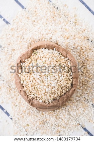 Rice grain in a paper bag over white kitchen table. View form above.