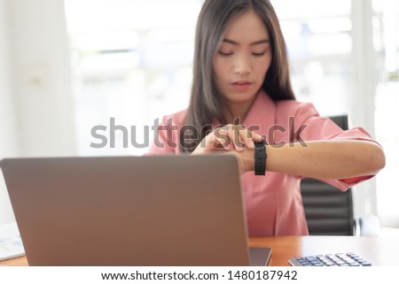 Asian businesswoman checking the time, work with laptop computer.