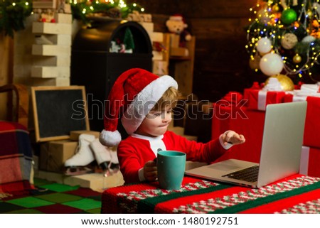 Smart toddler surfing internet. Little boy santa hat and costume. 