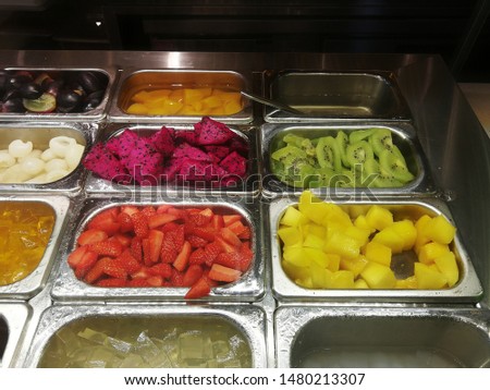 pieces of cut fruits of mango, strawberry, dragon fruit, kiwi in silver serving tray.