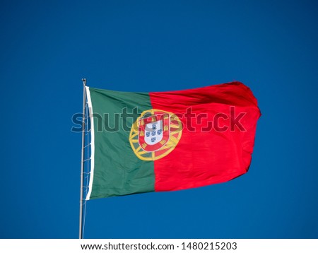 Large Portuguese flag waving in the wind against blue sky background. National symbol in Oeiras, Lisbon - Portugal
