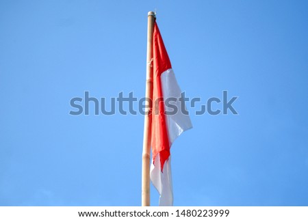 The Indonesian flag is red and white with a blue sky background