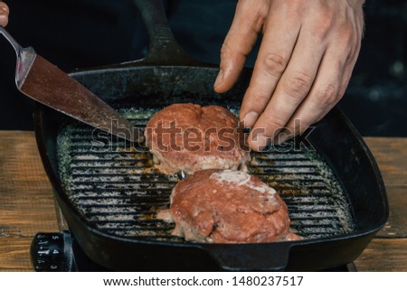 chef fries veal cutlet for grilled burger