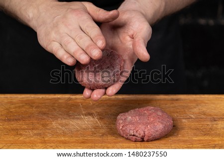 
the chef is shaping the meat of veal for burgers on a dark background
