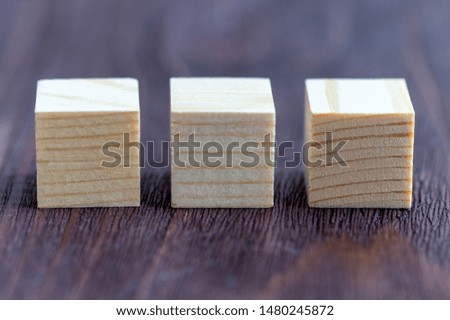 three wooden cubes on a Burgundy wooden background, space for your text, blank for design, selective focus, tinted image