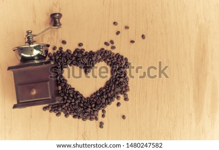 Roasted coffee beans arranged in a heart shape and old coffee grinder with space for text. Vintage style background.