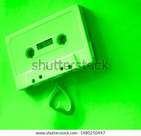 tape on green background with tape coming out of the cassette to form a red heart shape. Vintage audio cassette with loose tape shaping a heart on paper background