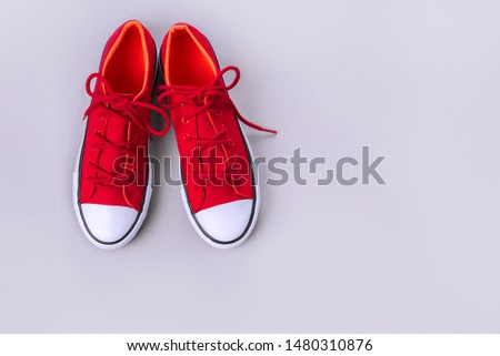 New red sneakers on grey background with copy space. Top view.