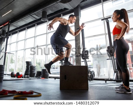 A muscular athletes doing workout at the gym. Gymnastics, training, fitness workout flexibility. Active and healthy lifestyle, youth, bodybuilding. Doing exercises together, training in jump with box.