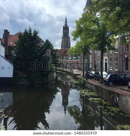 Picture of « Onze lieve vrouwetoren » which means the tower of our lady in the ancient dutch city of Amersfoort in summer in Holland with a canal in the foreground.