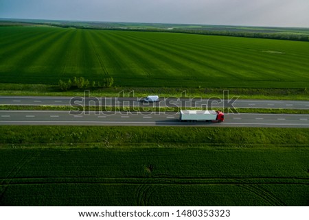 white trucks on the higthway sunset. cargo delivery driving on asphalt road along the green fields. seen from the air. Aerial view landscape. drone photography.