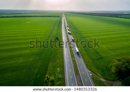 convoys with cargo. trucks on the higthway sunset. cargo delivery driving on asphalt road along the green fields. seen from the air. Aerial view landscape. drone photography.
