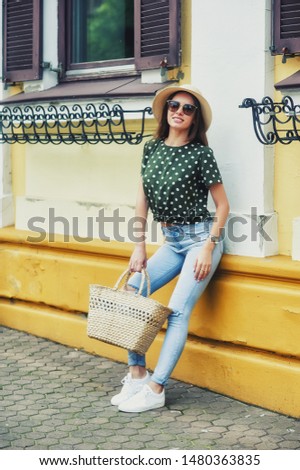 A young woman on the streets of a European city . A girl in jeans , a blouse and a wide-brimmed hat in the city . Street photography
