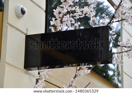 Empty black hanging sign with flowers in the background