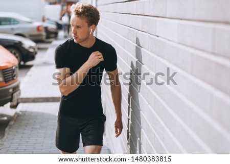 Young sports man stretching by the wall