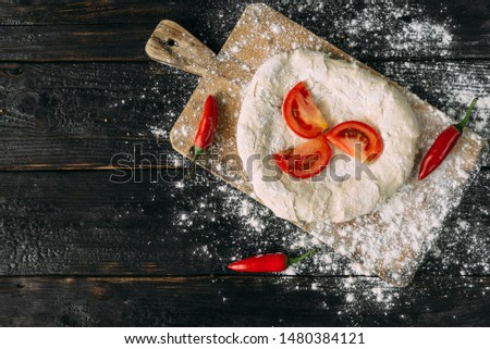 raw dough lies on the table, red tomatoes on a tortilla, place for text