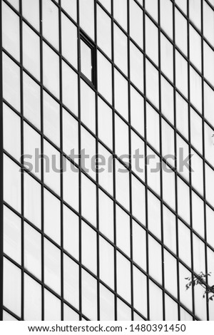 A high-rise office building with blue glass closed windows.Black and white toned photo