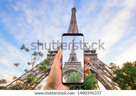 Hand holding the modern smartphone taking a picture of beautiful eiffel tower under blue sky, Eiffel Tower the most romantic tourist attraction and the symbol of Paris.