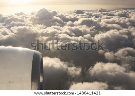Sky view on the plane. Beautiful sky above clouds with dramatic light in the evening. Cabin view and airplane engine. Golden hours