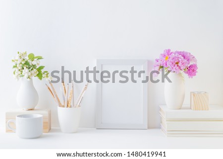 Home interior with decor elements. White frame, pink flowers in a vase, interior decoration
