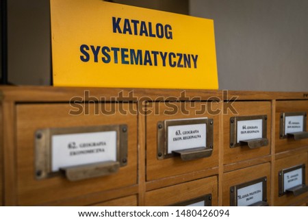 Photo of the file catalog in library in university in Poland, sign says "systematic catalog", labels say "local geography, political geography, ..." in Polish, selective focus