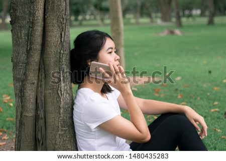 
Asian women communicate with mobile phones while sitting in the park, a refreshing environment.