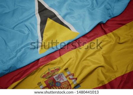 waving colorful flag of spain and national flag of saint lucia. macro