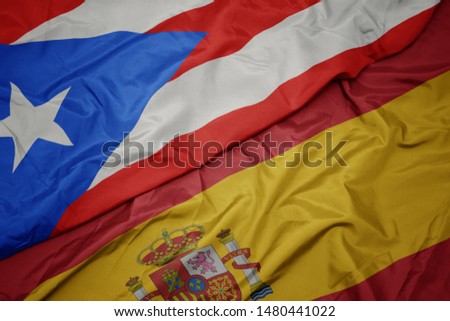 waving colorful flag of spain and national flag of puerto rico. macro