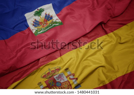 waving colorful flag of spain and national flag of haiti. macro